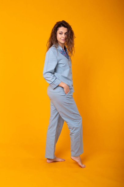 Young girl posing in pajamas on yellow background. Relax good mood, lifestyle and sleepwear concept. - Foto, Imagem