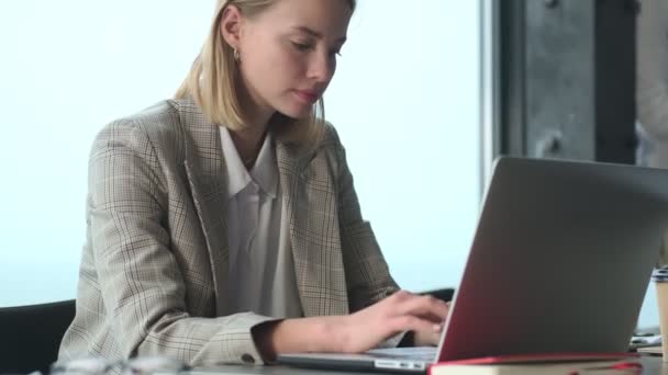Amazing concentrated blonde young business woman indoors in office using laptop computer - Imágenes, Vídeo