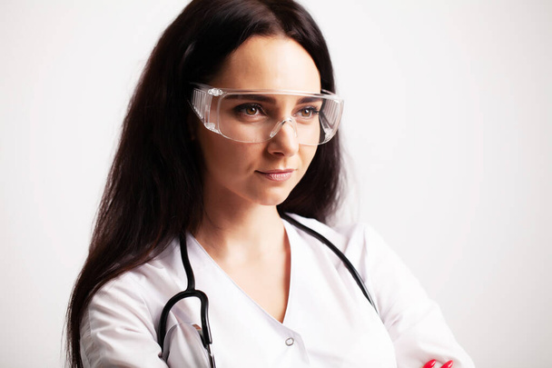 Doctor with protective goggles and stethoscope on her workspace - Photo, Image