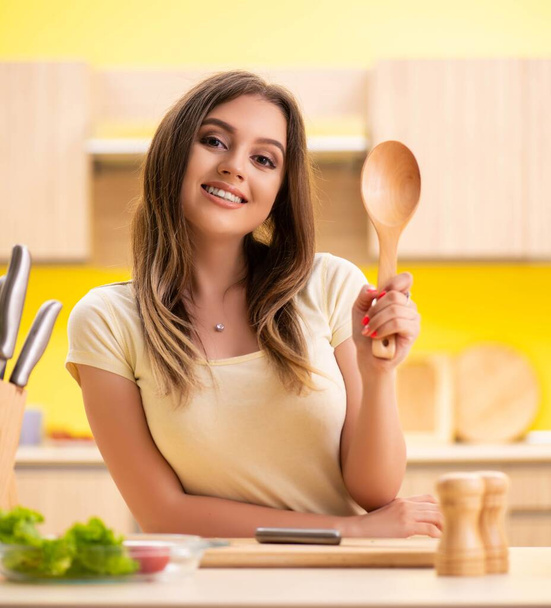 Fiatal nő készít salátát otthon a konyhában - Fotó, kép