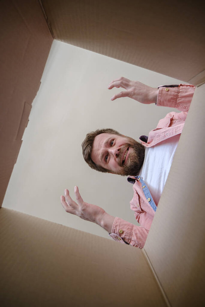 Расстроенный человек нашел неправильный заказ в распакованной коробке, он плачет и делает жест руками. Unboxing inside view
. - Фото, изображение