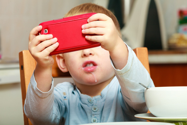 Boy taking photo with red mobile phone - Φωτογραφία, εικόνα
