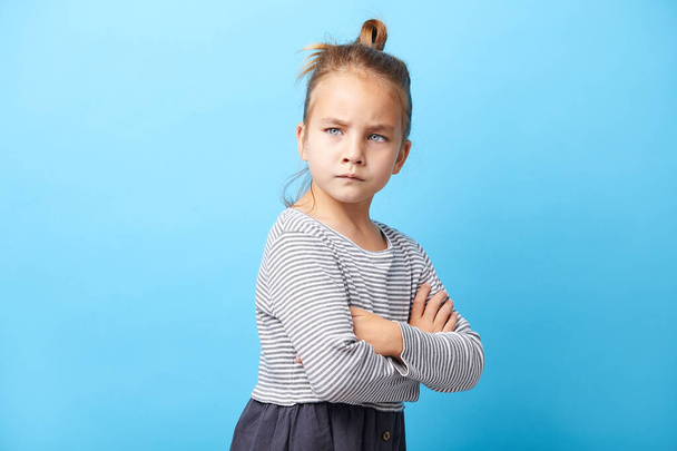 Angry little girl standing over white background, crossed her hands, sign and gesture concept. - Foto, Bild