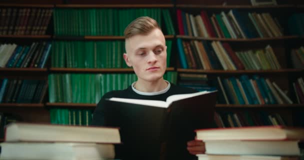 Der Mann versucht, die nötigen Informationen zu finden, indem er das Buch durchblättert. Bildung in der Bibliothek. 4K - Filmmaterial, Video