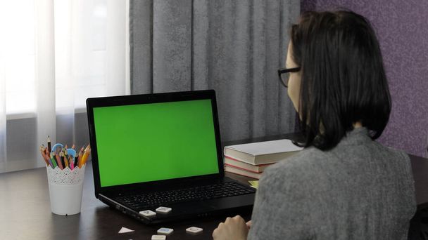 Mulher professora fazendo on-line chamada de vídeo educação a distância no laptop tela verde
 - Foto, Imagem