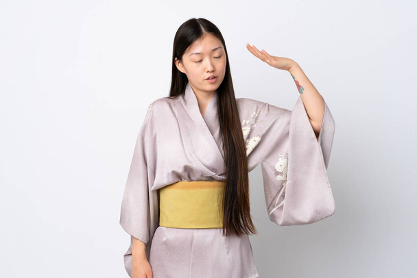 Młoda chińska dziewczyna nosi kimono na odosobnionym tle ze zmęczonym i chorym wyrazem twarzy - Zdjęcie, obraz