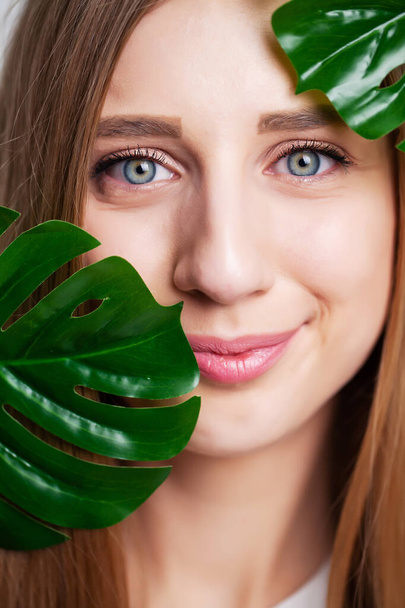 Kosmetyki naturalne, piękna twarz kobiety w zielonych liściach. - Zdjęcie, obraz