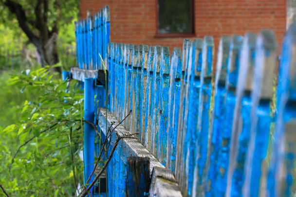 Sininen aita taustaa vasten tiili punainen talo kylässä kesällä
. - Valokuva, kuva