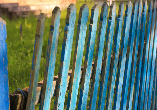 Zöld kerítés hátterében lédús fű a faluban nyáron. - Fotó, kép