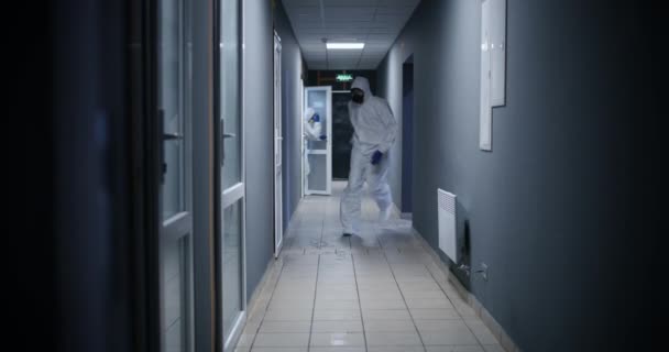 Hombres con traje de materiales peligrosos corriendo a través de un pasillo
 - Imágenes, Vídeo