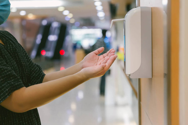Hands under the automatic alcohol dispenser. Infection and hospitably concept. save and protect disease virus against germs and clean in the public area.  - Foto, immagini