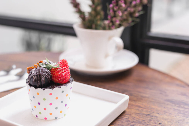 Leckere Tasse Kuchen mit Erdbeere auf Tischhintergrund. - Foto, Bild
