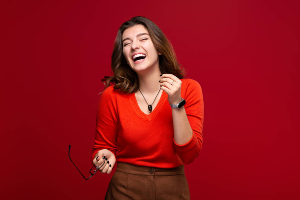 Cheerful young girl student with a smile, isolated on a red background. The concept of happiness and positive - Photo, Image