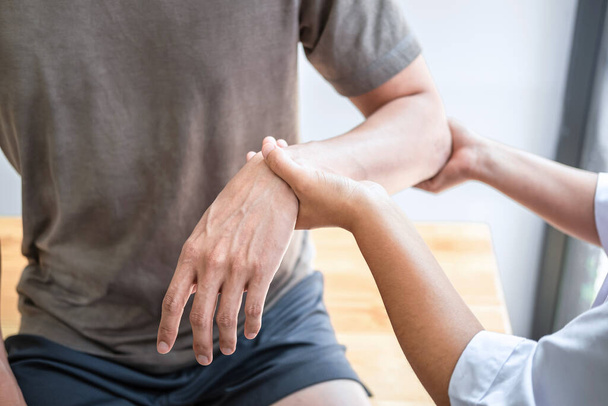 Vrouwelijke fysiotherapeut die onderzoek doet naar de behandeling van gewonde arm van atleet mannelijke patiënt, stretching en lichaamsbeweging, Doen van de revalidatietherapie pijn in de kliniek. - Foto, afbeelding