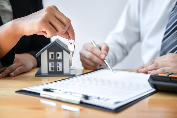 Home Insurance and Real estate investment concept, Sale agent giving house key to new client after signing agreement contract with approved property application form. - Photo, Image