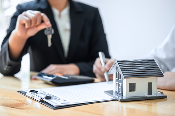 Концепція Home Insurance and Real estate investment, Sale Agent надає ключ від нового клієнта після підписання контракту з затвердженою формою заявки на нерухомість. - Фото, зображення