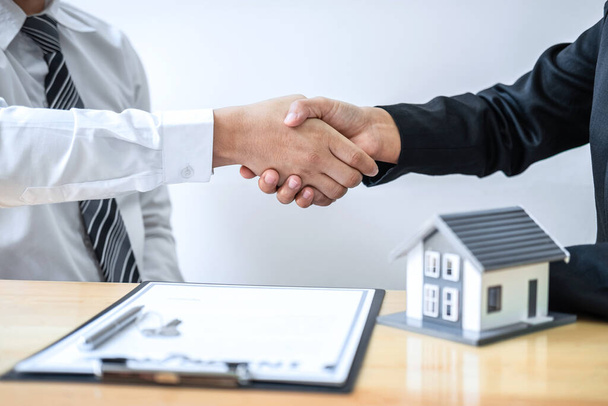 Real estate agent are shaking hands after good deal and giving house, keys to customer after discussing and signing contract to buy house with approved application form. - Φωτογραφία, εικόνα