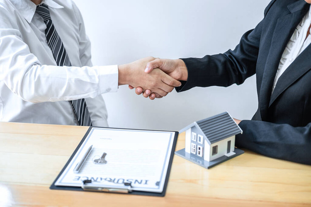 Real estate agent are shaking hands after good deal and giving house, keys to customer after discussing and signing contract to buy house with approved application form. - Photo, Image