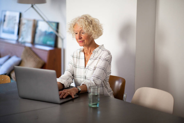 Portrait older woman using laptop computer at home - Foto, Bild