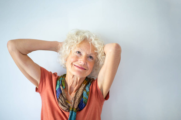 Close up retrato mulher idosa sorrindo com as mãos atrás da cabeça por fundo branco
 - Foto, Imagem