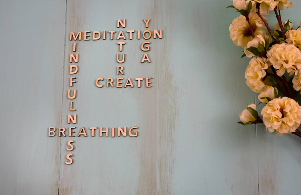 Houten kruiswoordpuzzels die geestelijke gezondheid ondersteunen en omgaan met strategieën, meditatie, natuur, yoga creativiteit, mindfulness, ademhaling concept met kopieerruimte en bloemen  - Foto, afbeelding