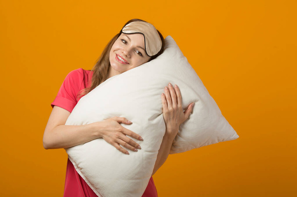  beautiful young woman in a pink dress on a yellow background with a pillow - Fotó, kép