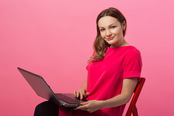 beautiful young woman with laptop on pink background with hand gesture - Φωτογραφία, εικόνα