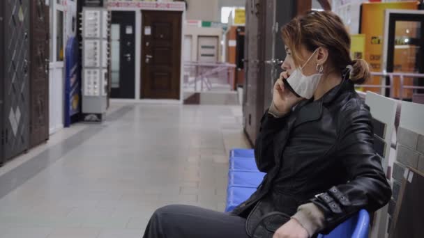 Una mujer de negocios con una máscara protectora se comunica en un centro comercial
 - Metraje, vídeo