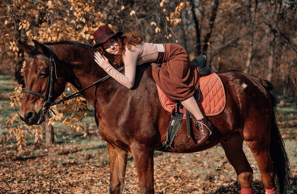 Portret van een prachtige roodharige vrouw met paard buiten. - Foto, afbeelding