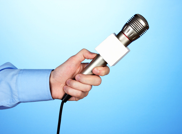 Male hand with microphone on blue background - Φωτογραφία, εικόνα