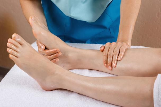 A woman came to a professional for foot massage. Close-up of female legs. Professional masseur doing foot massage - Φωτογραφία, εικόνα