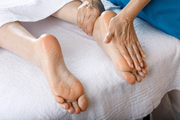 A woman came to a professional for foot massage. Close-up of female legs. Professional masseur doing foot massage - Фото, изображение