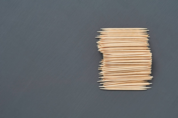 Heap of wooden toothpicks lies on black concrete desk on kitchen. Space for text. Top view - Valokuva, kuva