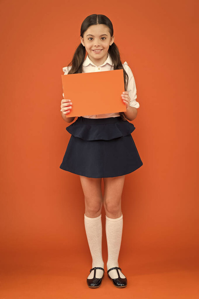 writing notes. kid diary. poetry and novel. modern education. school girl read book on orange background. happy little girl in school uniform with notebook. literature lesson. back to school - 写真・画像