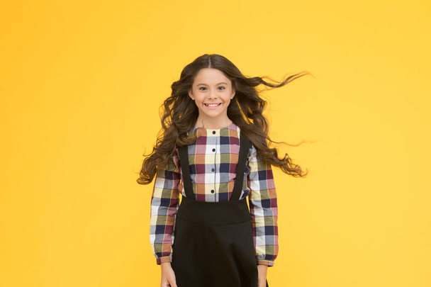Salon interested in my hair. Happy child with long hair yellow background. Small girl with wavy brunette hair. Back to school hairstyle. Hair salon. Beauty salon. Salon care. Haircare habit - Foto, afbeelding
