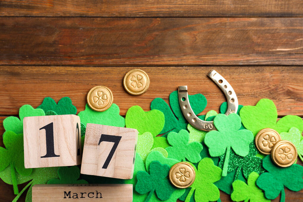 Flat lay composition with horseshoe and block calendar on wooden background, space for text. St. Patrick's Day celebration - Foto, afbeelding