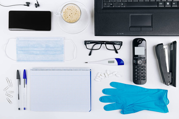 温度計、手袋とCovid 19コロナウイルスを避けるためのマスクであなたの健康を世話する自宅でのオンライン作業のためのオフィス用品. - 写真・画像