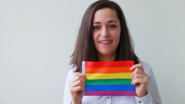 Krásná kavkazská lesbická dívka s LGBT duhovou vlajkou izolované na bílém pozadí vypadá šťastně a vzrušeně. Mladá žena, portrét Gay Pride. Rovná práva pro komunitní koncept lgbtq - Záběry, video