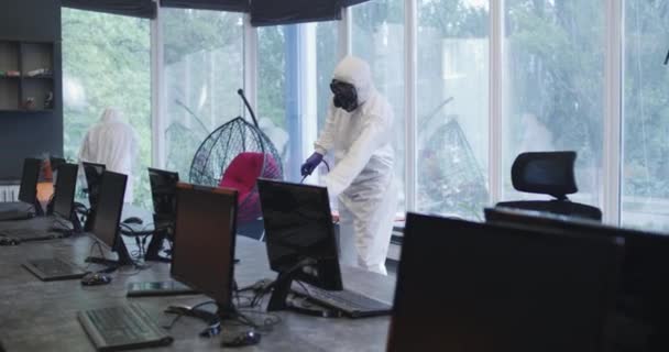 Hombres con trajes de materiales peligrosos desinfectando la oficina
 - Imágenes, Vídeo