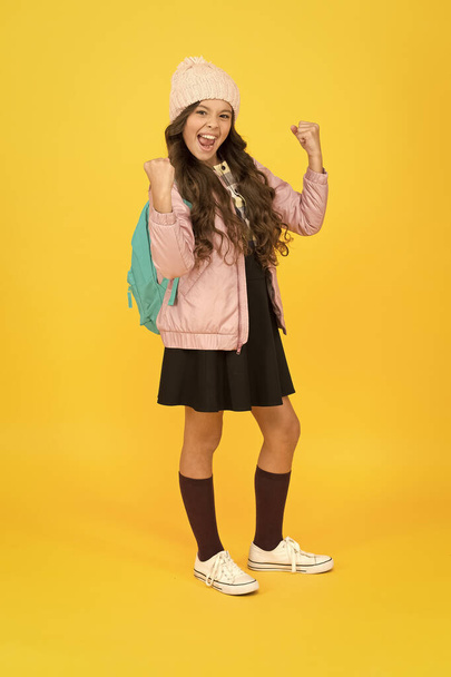 Finally succeed. Modern outfit. Fashion accessory. Girl smiling face little fashionable cutie wear knitted hat and jacket. Adorable schoolgirl winter outfit. Schoolgirl tidy outfit with backpack - Φωτογραφία, εικόνα