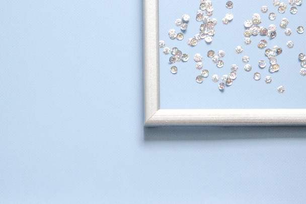 Part of the silver frame is decorated with confetti with space for text on blue background. - Fotoğraf, Görsel