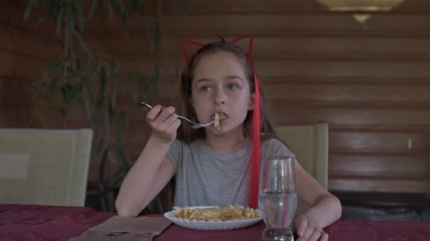 Маленька дівчинка їсть картоплю фрі у ресторані швидкого харчування. Дівчина їсть картоплю фрі. Маленька дівчинка обідала в кафе
. - Кадри, відео
