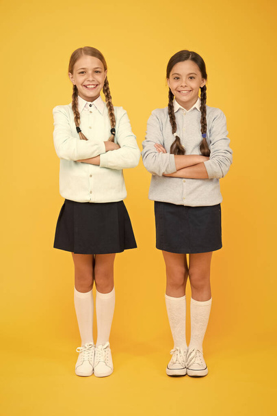 Finally graduated. knowledge day. childhood happiness. smart little girls on yellow background. education concept. back to school. girls in school uniform. kid fashion. Friendship and sisterhood - Foto, afbeelding