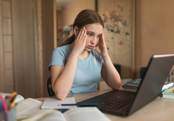 Väsynyt tyttö on teini-ikäinen 12-15-vuotias, stressi ja masennus, astenia ja turhautuminen kotona, opiskelu Internetissä, kannettava tietokone Internet. Etäopetus karanteenin aikana, pysy kotona
. - Valokuva, kuva
