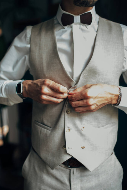 Close-up of a man in a tux fixing his cufflink. groom bow tie cufflinks. - Фото, зображення
