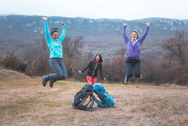 Three girls, hikers, happy and smiling posing for photo, jumping up in the air. Hiking, backpacking - Foto, Imagem
