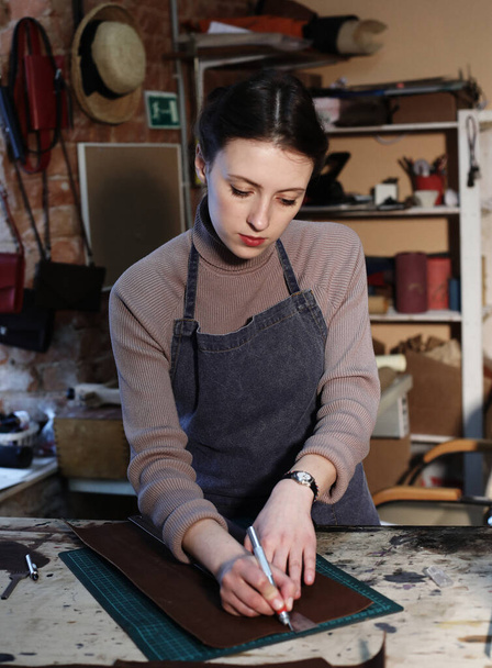 young woman works in a bag making studio, cuts out details - Foto, immagini
