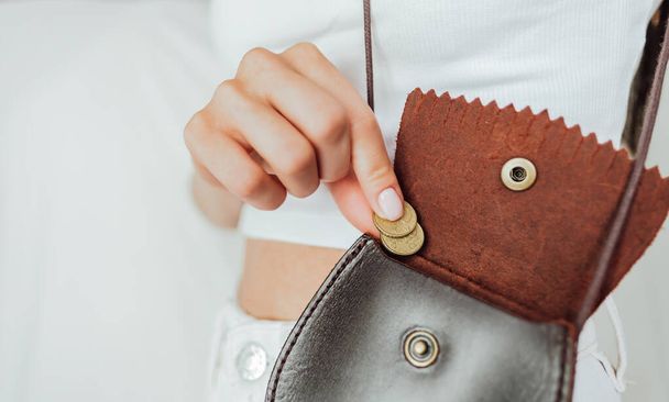 Girl puts a coin in the leather purse. - Zdjęcie, obraz