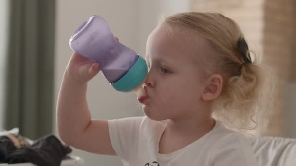 Little child drinking milk from the bottle - Кадри, відео