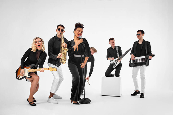 photo of multi ethnic music band in studio.Musicians and woman soloist posing over white background - Photo, Image